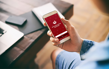man holding cell phone looking at AHA Knowledge Booster