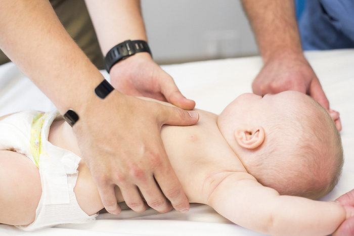 teaching thumbs CPR technique on infant image