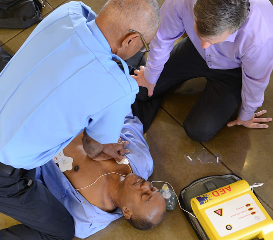 Paramedic using AED on man with bystander watching image