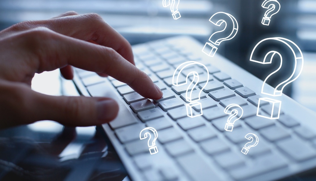 floating question marks over a keyboard illustrating FAQs image
